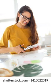 Young Brunette Woman Creating Her Feng Shui Wish Map Using Scissors