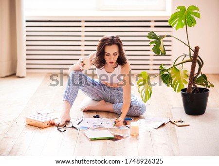 Young brunette woman creating her Feng Shui wish map using scissors. Dreams and wishes