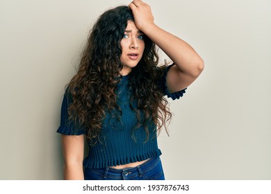 Young Brunette Woman With Curly Hair Wearing Casual Clothes Surprised With Hand On Head For Mistake, Remember Error. Forgot, Bad Memory Concept. 