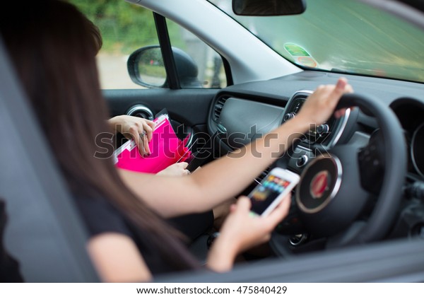 young brunette woman driving a black car\
outside. Rudder. Keep your phone in your\
hands