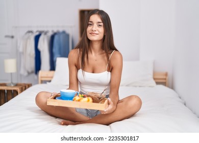 Young brunette woman eating breakfast in the bed relaxed with serious expression on face. simple and natural looking at the camera.  - Powered by Shutterstock