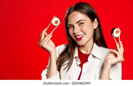 Young Brunette Woman Girl In Casual Clothes Hold In Hand Makizushi Sushi Roll, Traditional Japanese Food Isolated On Red Background Studio Portrait. Restaurants And Takeout Concept