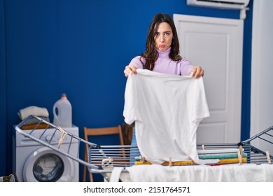 Young Brunette Woman Hanging Clothes At Clothesline Depressed And Worry For Distress, Crying Angry And Afraid. Sad Expression. 