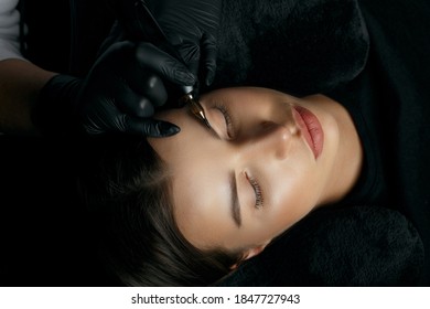Young brunette woman having eyebrow permanent procedure at the beauty salon. Top view