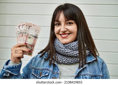 Young Brunette Woman Holding Arabia Saudi Riyal Banknotes By Shutter Door