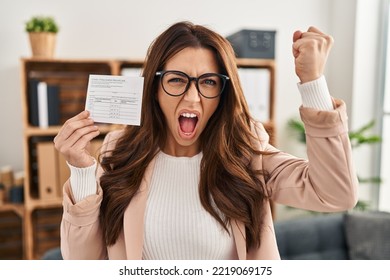 Young Brunette Woman Holding Covid Record Card Annoyed And Frustrated Shouting With Anger, Yelling Crazy With Anger And Hand Raised 