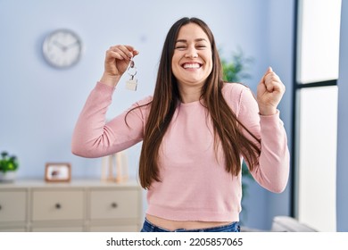 Young Brunette Woman Holding Keys Of New Home Screaming Proud, Celebrating Victory And Success Very Excited With Raised Arm 