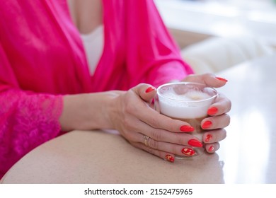 Young Brunette Woman In Kitchen Wearing Pink Dressing Gown With A Cup Of Hot Beverage Coffee. Tender Woman Portrait During Morning Routine And Breakfast.