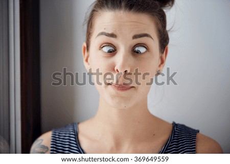Young brunette woman looking cross-eyed. Closeup shot with wide angle and focus on the eyes. Harsh processing to emphasize the face structure. Human face expression body language reaction