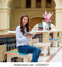 Young brunette woman making notes in a notebook sitting in the mall - Shutterstock ID 623296277