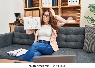 Young Brunette Woman On Therapy Session Working At Consultation Office Stressed And Frustrated With Hand On Head, Surprised And Angry Face 