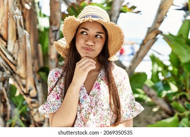 Young brunette woman outdoors on a sunny day of summer smiling happy and positive, thumb up doing excellent and approval sign 