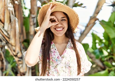 Young brunette woman outdoors on a sunny day of summer pointing thumb up to the side smiling happy with open mouth 