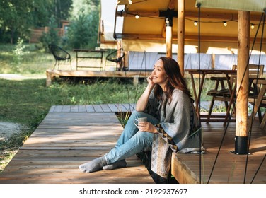 Young brunette woman in poncho drinking tea and relaxing in glamping in nature - Powered by Shutterstock