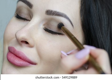 Young Brunette Woman Putting Make Up On Face With Cosmetic Brush