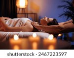 Young brunette woman receives a professional head and shoulders massage in spa salon. A beautiful lady in a towel with perfect skin gets a relaxing massage. The concept of luxury professional massage.