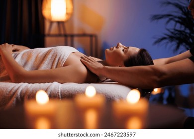 Young brunette woman receives a professional head and shoulders massage in spa salon. A beautiful lady in a towel with perfect skin gets a relaxing massage. The concept of luxury professional massage. - Powered by Shutterstock