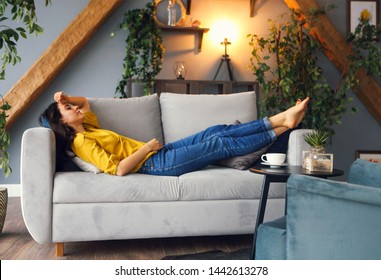 Junge brunette Frau entspannend auf dem Sofa nach einem langen Tag. Gemütliches Wohnkonzept