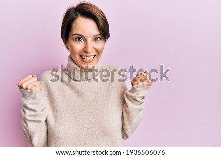 Young brunette woman with short hair wearing casual winter sweater celebrating surprised and amazed for success with arms raised and open eyes. winner concept. 