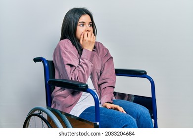 Young brunette woman sitting on wheelchair looking stressed and nervous with hands on mouth biting nails. anxiety problem.  - Powered by Shutterstock