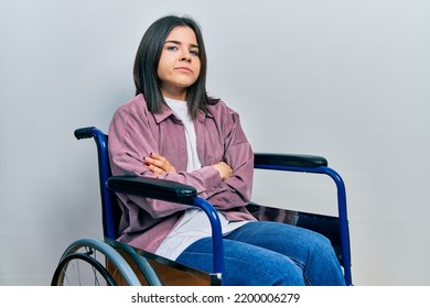 Young brunette woman sitting on wheelchair skeptic and nervous, disapproving expression on face with crossed arms. negative person.  - Powered by Shutterstock