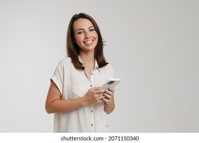 Young brunette woman smiling while using cellphone isolated over white background - Shutterstock ID 2071150340