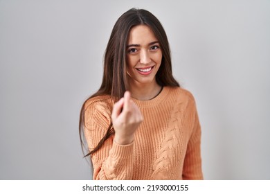 Young Brunette Woman Standing Over White Background Beckoning Come Here Gesture With Hand Inviting Welcoming Happy And Smiling 