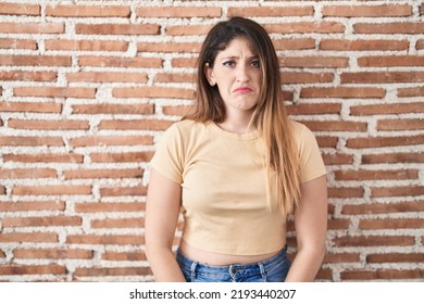 Young Brunette Woman Standing Over Bricks Wall Depressed And Worry For Distress, Crying Angry And Afraid. Sad Expression. 