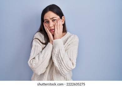 Young brunette woman standing over blue background tired hands covering face, depression and sadness, upset and irritated for problem  - Shutterstock ID 2222635275