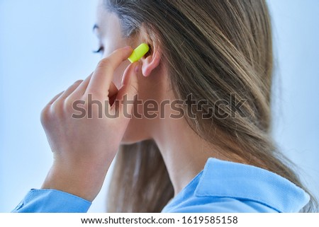 Young brunette woman using earplugs for noise protection 