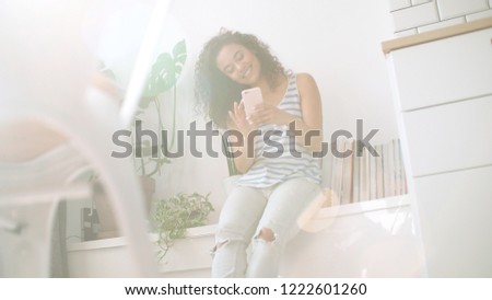 Young brunette woman using mobile phone at home.