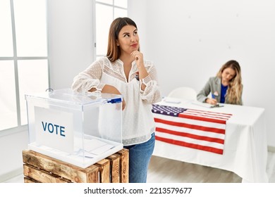 Young Brunette Woman Voting Putting Envelop In Ballot Box Serious Face Thinking About Question With Hand On Chin, Thoughtful About Confusing Idea 