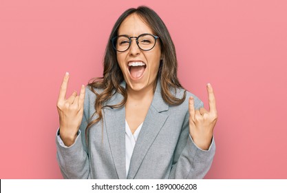 Young Brunette Woman Wearing Business Clothes Shouting With Crazy Expression Doing Rock Symbol With Hands Up. Music Star. Heavy Concept. 