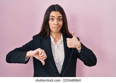 Young brunette woman wearing business style over pink background doing thumbs up and down, disagreement and agreement expression. crazy conflict  - Shutterstock ID 2255680869