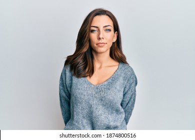 Young brunette woman wearing casual winter sweater relaxed with serious expression on face. simple and natural looking at the camera. 