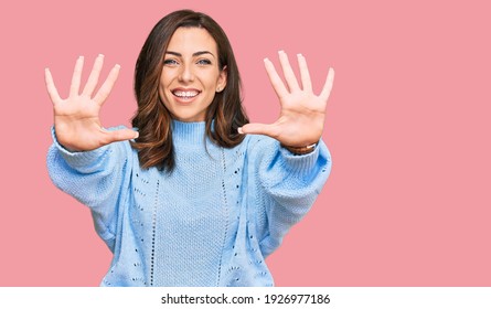Young brunette woman wearing casual winter sweater showing and pointing up with fingers number ten while smiling confident and happy. 