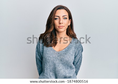 Young brunette woman wearing casual winter sweater relaxed with serious expression on face. simple and natural looking at the camera. 