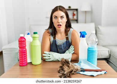 Young Brunette Woman Wearing Cleaner Apron And Gloves Cleaning At Home Afraid And Shocked With Surprise Expression, Fear And Excited Face. 