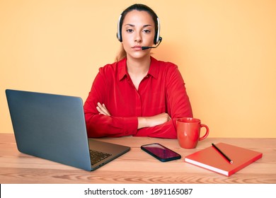Young brunette woman wearing operator headset at the call center office with serious expression on face. simple and natural looking at the camera. 