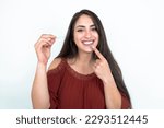 young brunette woman wearing red shirt over white studio background holding an invisible aligner and pointing to her perfect straight teeth. Dental healthcare and confidence concept.