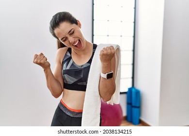 Young brunette woman wearing sportswear and towel at the gym very happy and excited doing winner gesture with arms raised, smiling and screaming for success. celebration concept.  - Powered by Shutterstock