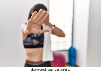 Young brunette woman wearing sportswear and towel at the gym covering eyes with hands and doing stop gesture with sad and fear expression. embarrassed and negative concept. 