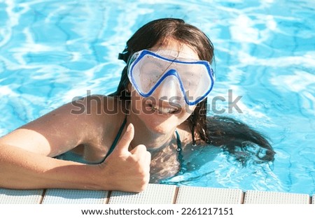 Young brunette woman wearing swimming mask relaxing in a pool at summer. Happy time.