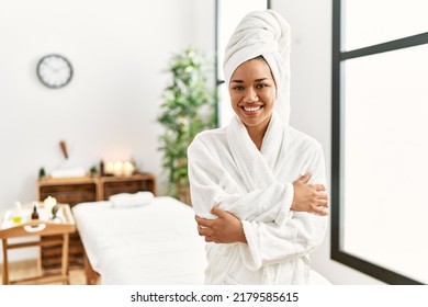 Young Brunette Woman Wearing Towel And Bathrobe Standing At Beauty Center Happy Face Smiling With Crossed Arms Looking At The Camera. Positive Person. 