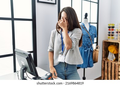 Young brunette woman working as manager at retail boutique tired rubbing nose and eyes feeling fatigue and headache. stress and frustration concept. 