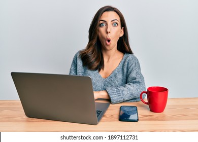 Young Brunette Woman Working At The Office Using Computer Laptop Scared And Amazed With Open Mouth For Surprise, Disbelief Face 