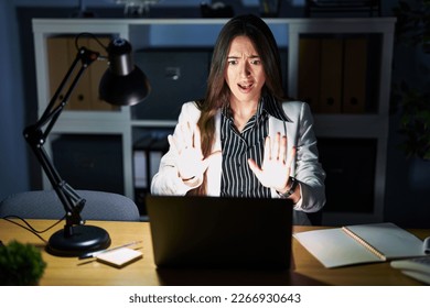Young brunette woman working at the office at night with laptop doing stop gesture with hands palms, angry and frustration expression  - Shutterstock ID 2266930643