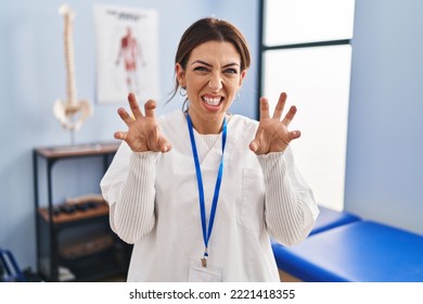 Young Brunette Woman Working At Pain Recovery Clinic Smiling Funny Doing Claw Gesture As Cat, Aggressive And Sexy Expression 