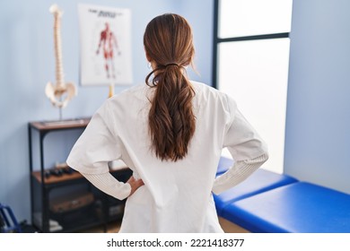 Young Brunette Woman Working At Pain Recovery Clinic Standing Backwards Looking Away With Arms On Body 