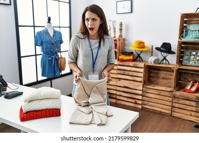 Young brunette woman working at retail boutique angry and mad screaming frustrated and furious, shouting with anger. rage and aggressive concept. 